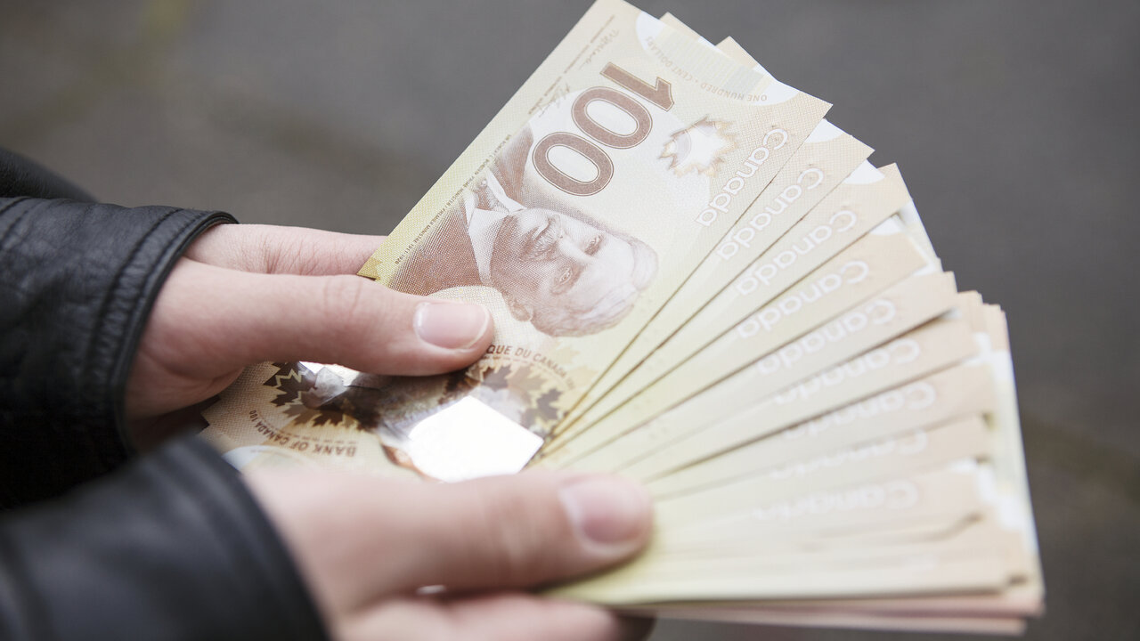 Manos sosteniendo billetes de cien dólares canadienses. (Cortesía de Fxstreet)